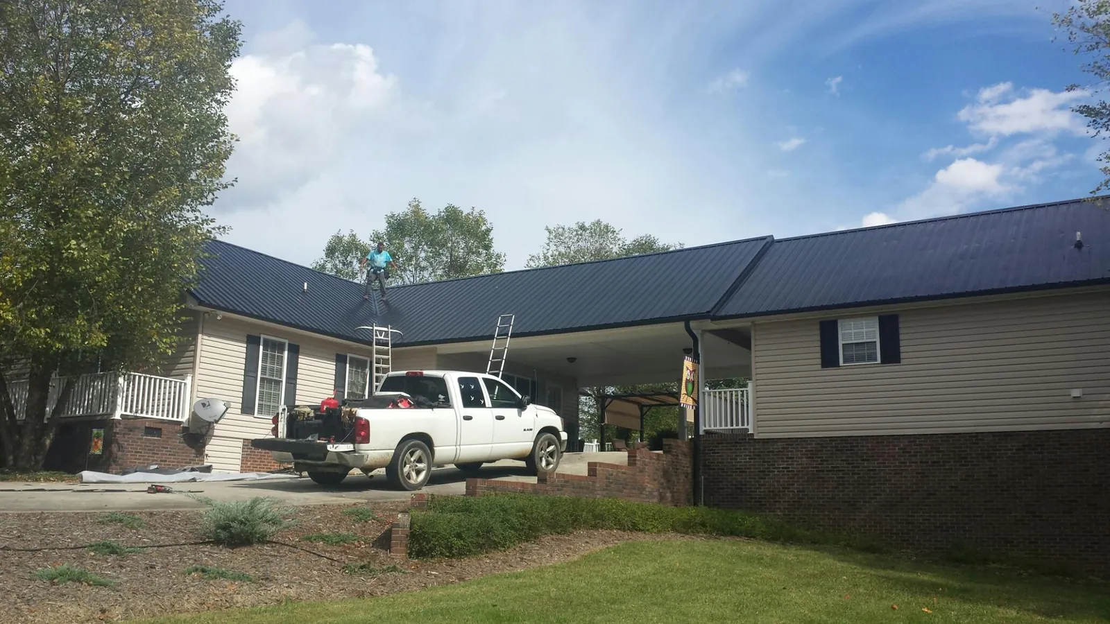 Black metal roof over a home and attached breezeway with ladders set in Wayne